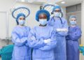 Group of medical surgeons wearing hospital scrubs in operating theatre ...