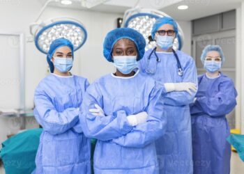 Group of medical surgeons wearing hospital scrubs in operating theatre ...