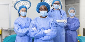Group of medical surgeons wearing hospital scrubs in operating theatre ...
